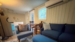 Un salon avec un canapé bleu, un tapis à motifs et un coin repas comprenant une table et des chaises.