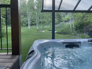 A hot tub with a view of a grassy area and trees.