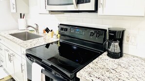A kitchen with white cabinets, a microwave, a stove, a coffee maker, and a sink. - 2BRpartment,LasVegas,Strip,Pet-friendly,Lvcc,SALE,BestSpot,Sema Show,Labor day (Las Vegas)