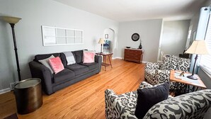 A living room with a black sofa, patterned armchairs, a wooden coffee table, a lamp, a dresser, and a framed artwork on the wall. - Make your visit to the beautiful city of Berea memorable! (Berea)