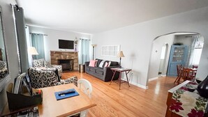 A living room with a fireplace, a sofa, a dining table, and a TV mounted on the wall. - Make your visit to the beautiful city of Berea memorable! (Berea)