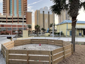 Relax in a well-maintained outdoor space with a sandy play area and sports facilities, including a basketball hoop.
