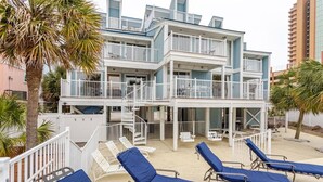 Un edificio de varios pisos con balcones, un área de piscina con tumbonas y palmeras.