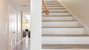 Una escalera de madera con barandilla que lleva a un rellano con una puerta y una ventana.