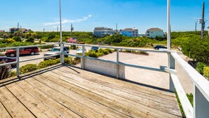 A wooden deck with a view of a parking area and buildings in the background.