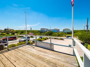 A wooden deck with a view of a parking area and buildings in the background.