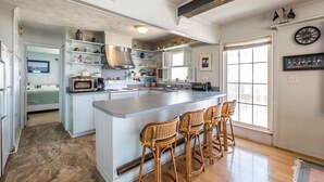 A spacious kitchen with a large island, white cabinetry, and a rustic ceiling.