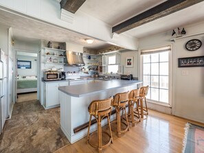 A spacious kitchen with a large island, white cabinetry, and a rustic ceiling.
