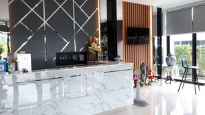 A modern reception area with a marble counter, a clock, and a TV.