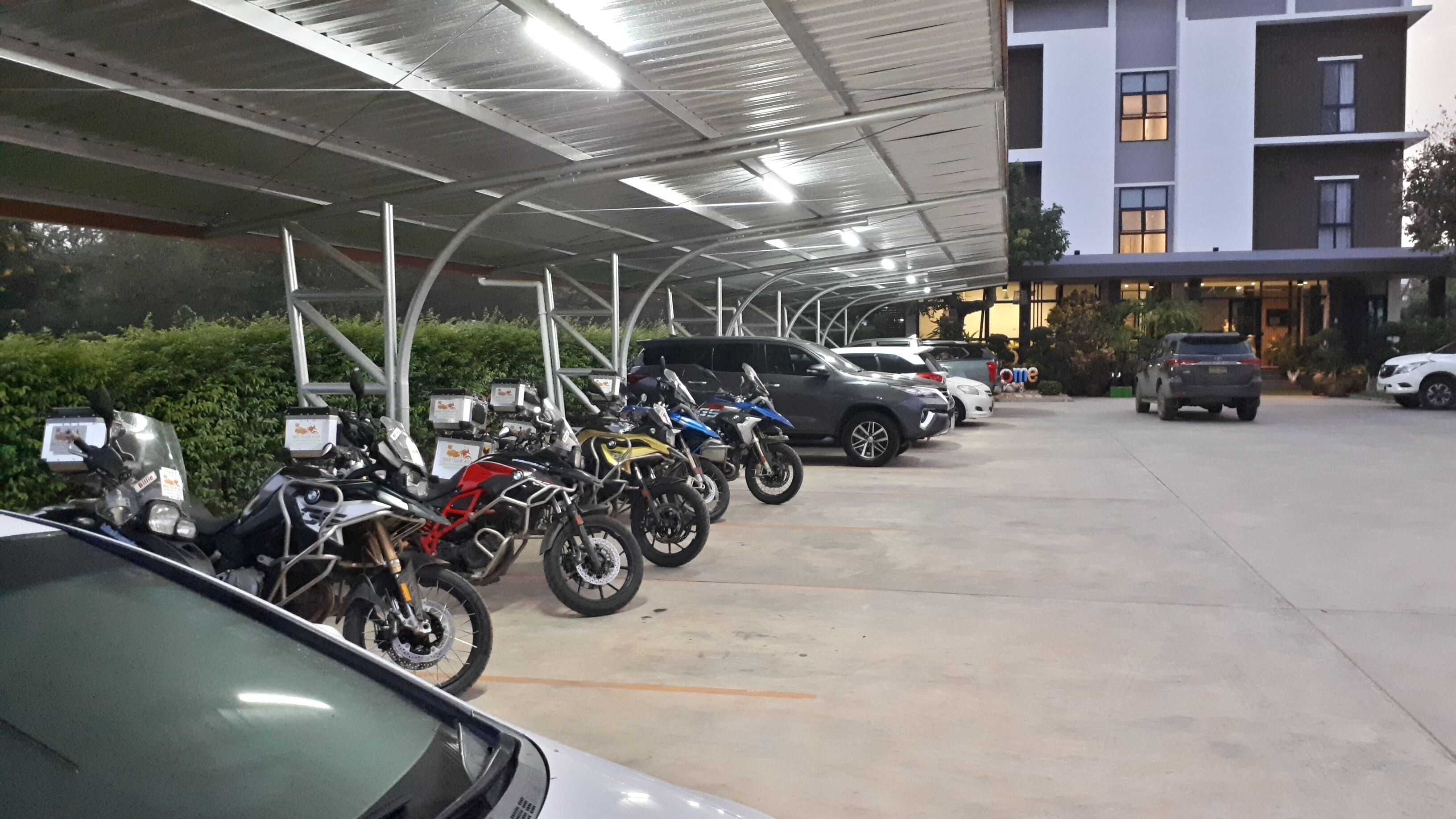 Un área de estacionamiento techada con motocicletas y automóviles aparcados.