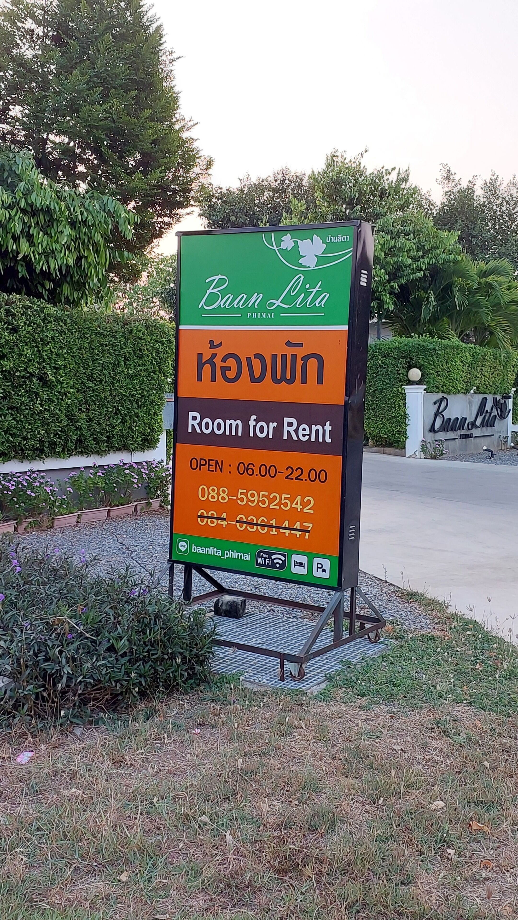 A sign for Baan Lita Phimai, a room for rent, with operating hours and contact numbers.