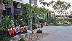 A well-maintained garden with a 'Welcome' sign, various potted plants, and decorative elements like animal figures.