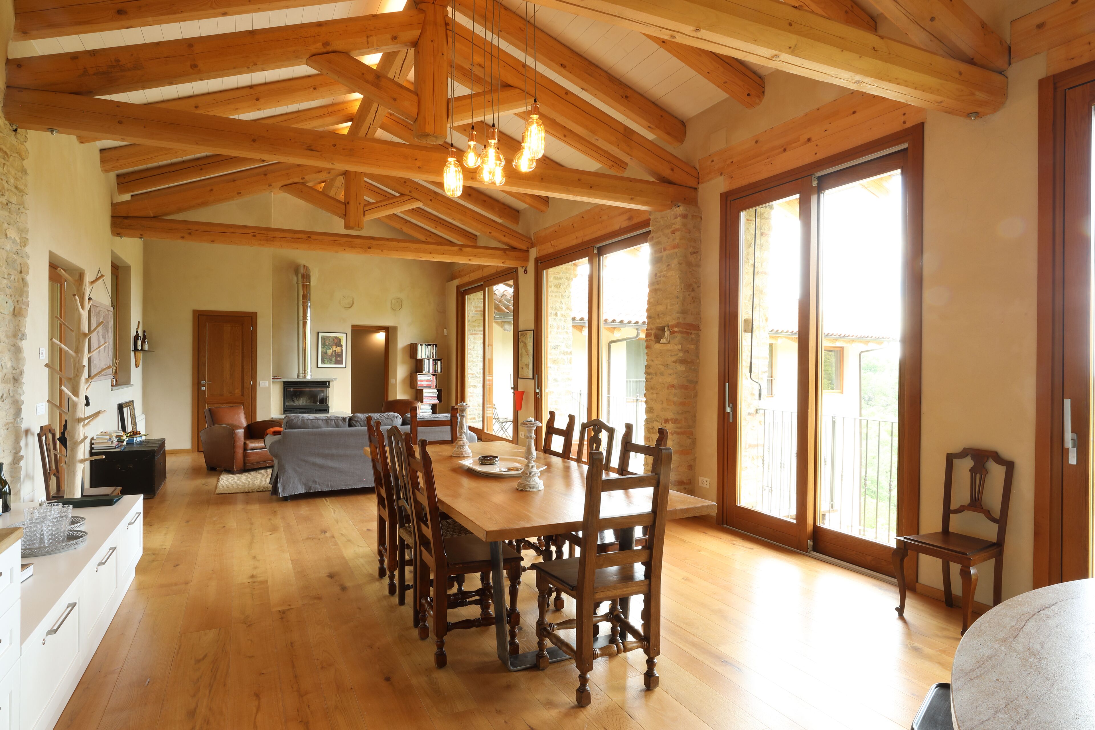A spacious dining area with a wooden table and chairs, a fireplace, and large windows.