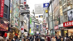 Une rue animée en milieu urbain, avec des piétons et divers commerces.