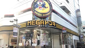 Un cinéma avec une grande enseigne sur laquelle on peut lire « BIENVENUE AU MEGA DONKI » et « MEGA DONKI » en lettres bien visibles.