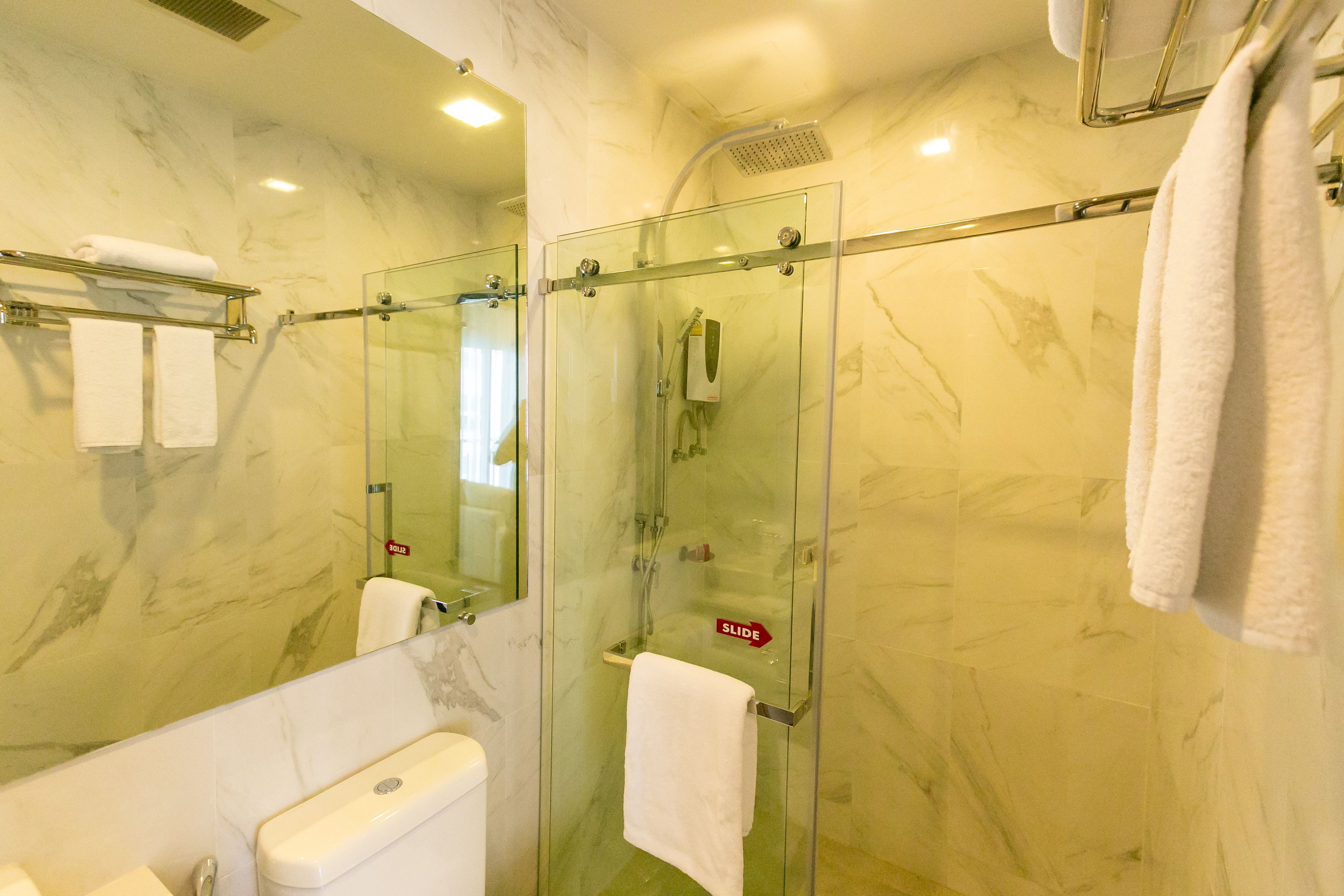 A bathroom with a glass-enclosed shower, a toilet, and a sink.