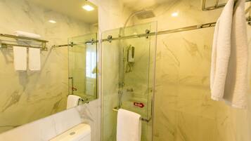 A bathroom with a glass-enclosed shower, a toilet, and a sink.