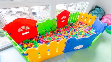 Un'area giochi al coperto colorata, con una piscina di palline e strutture ricreative.