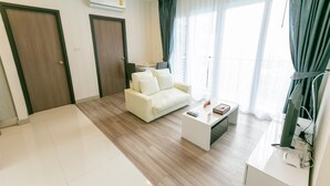 A modern living room with a white sofa, a coffee table, and a TV. There are two doors, one of which has a window. - Locals ChiangMai Central Airport Plaza (Chiang Mai)
