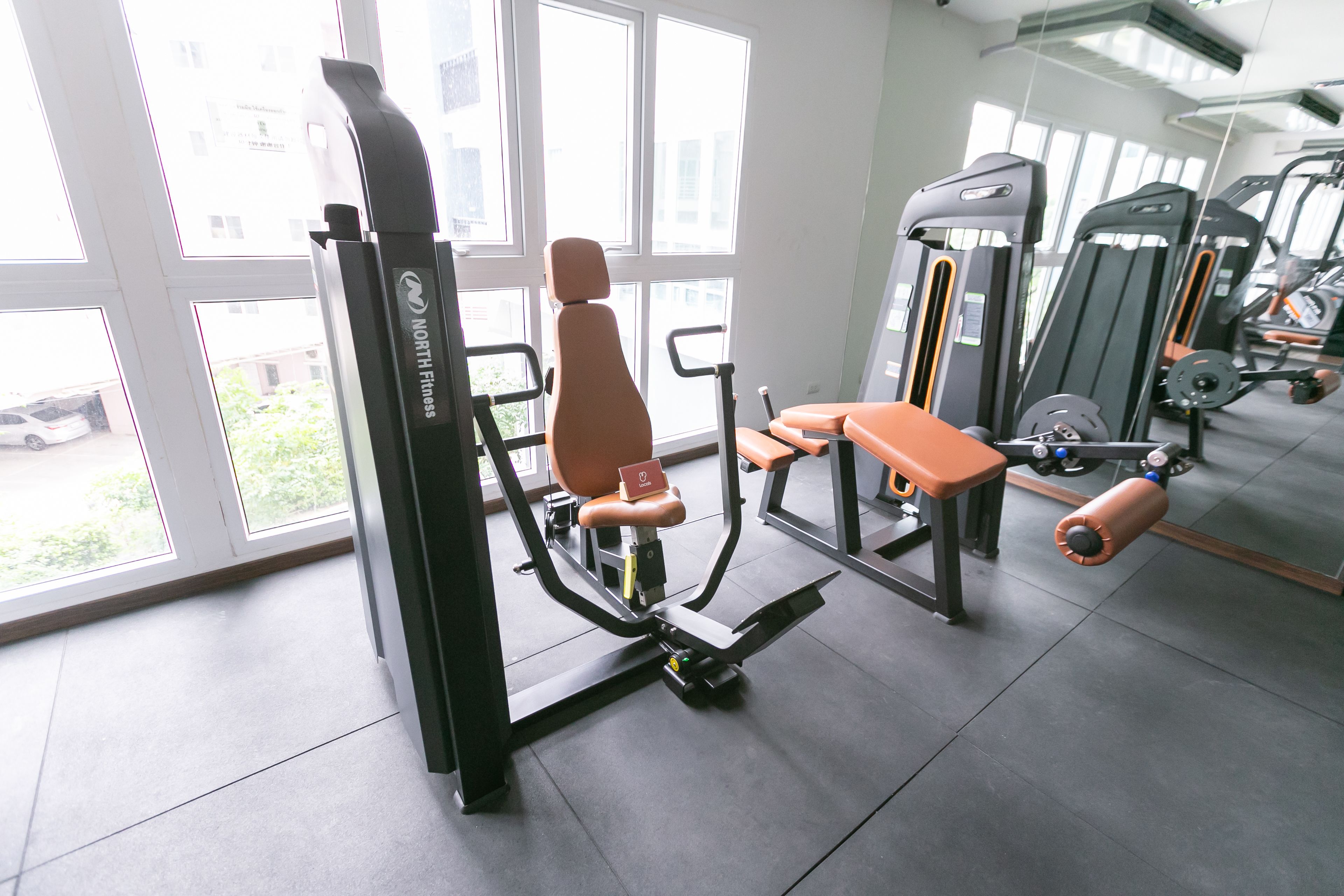 A gym with exercise equipment, large windows, and a view of the outside.
