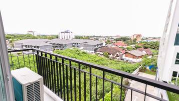 Een woonwijk met moderne gebouwen, een balkon met een zwarte balustrade en een airconditioning.