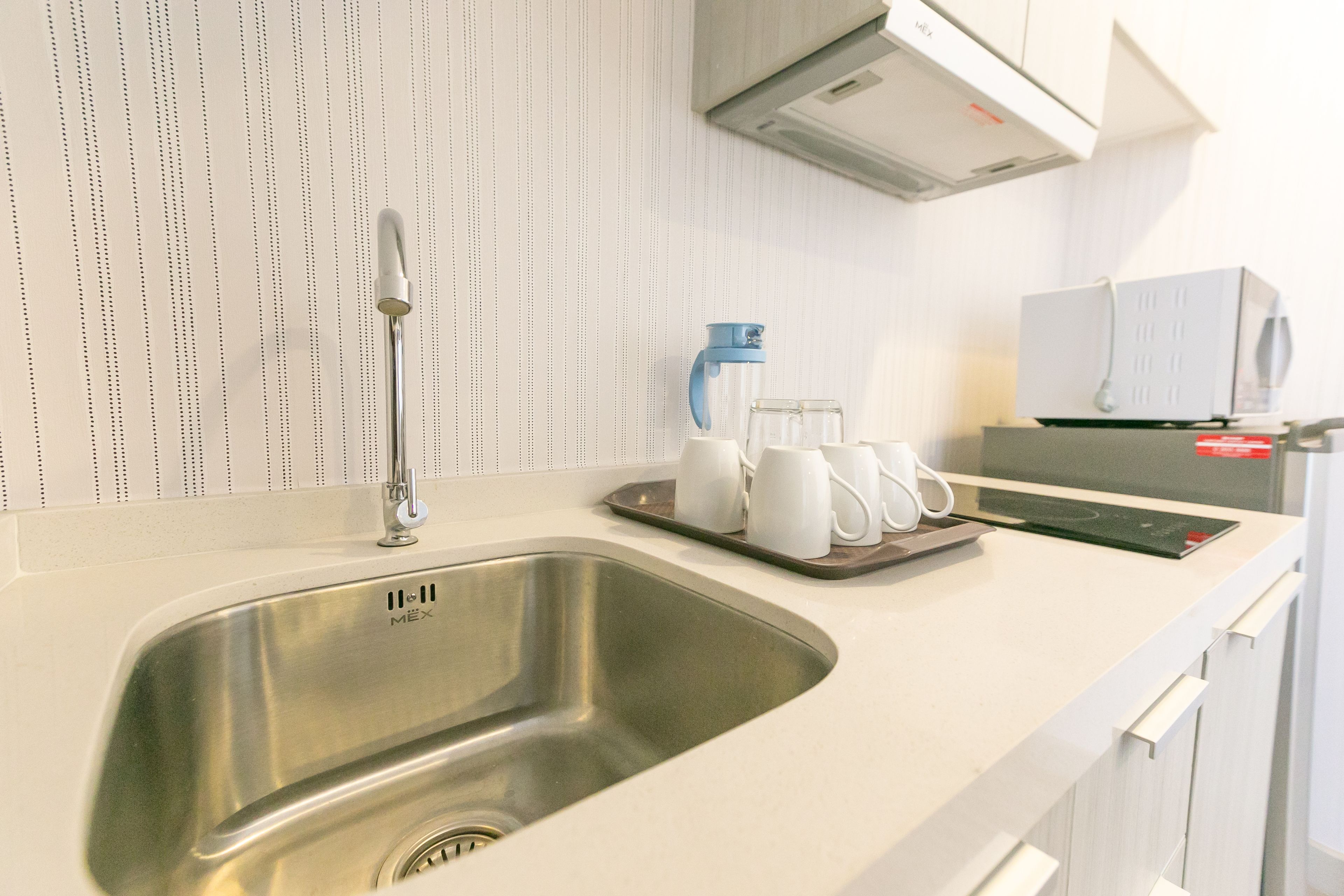 Una cocina moderna con un lavamanos de acero inoxidable, armarios blancos y una cafetera en la encimera.