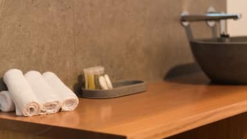 A wooden counter with rolled towels and a soap dish.
