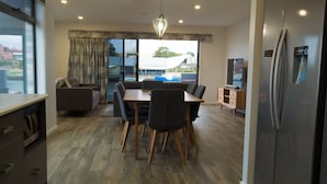 Una cocina moderna con comedor, piso de madera y refrigerador.