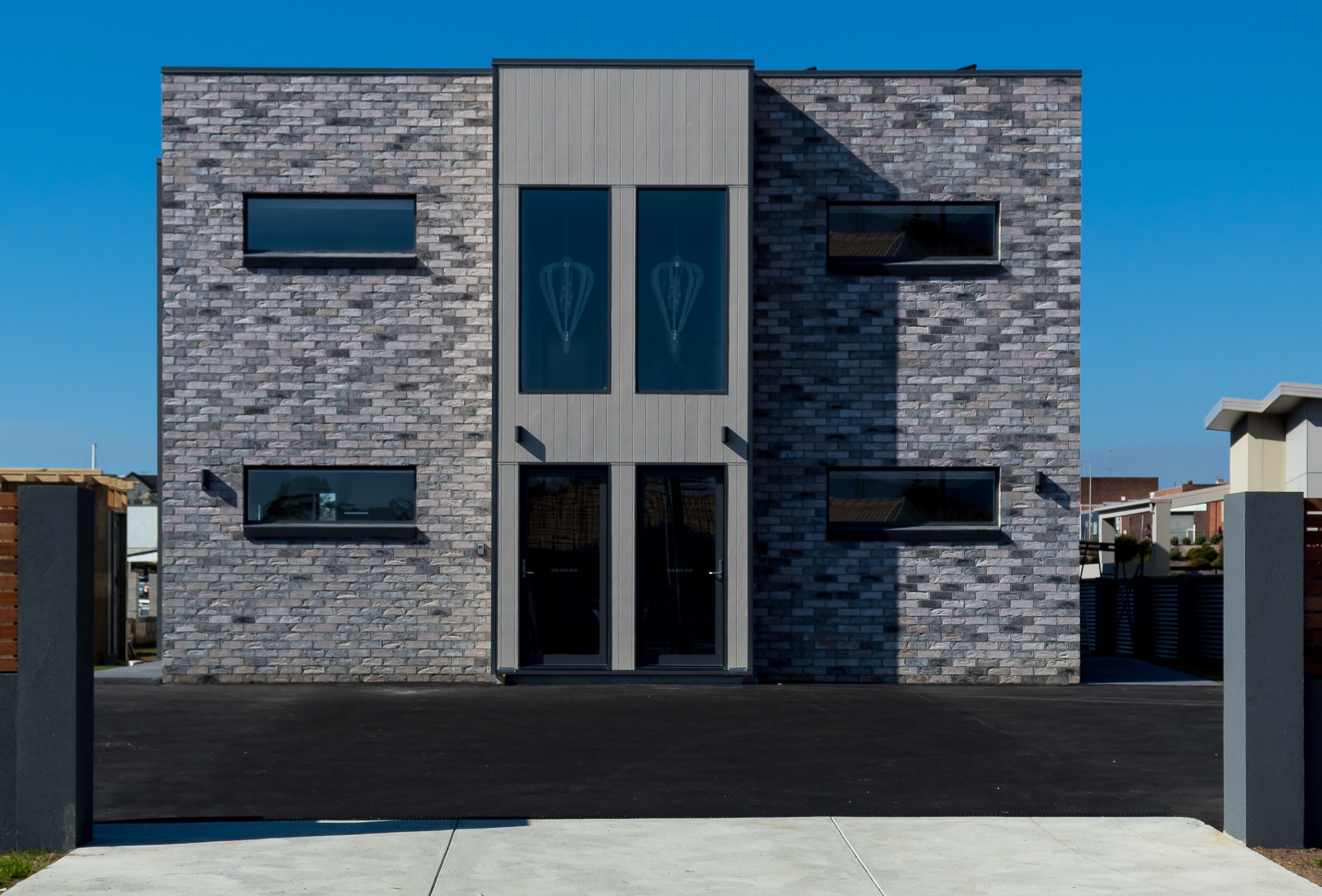 A modern building with a stone facade, large windows, and a black roof.