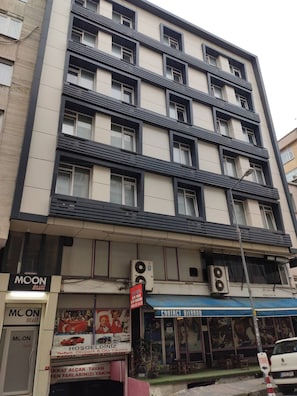 Un edificio de varios pisos con varios locales comerciales en la planta baja, incluyendo una tienda de trajes y un centro de contacto.