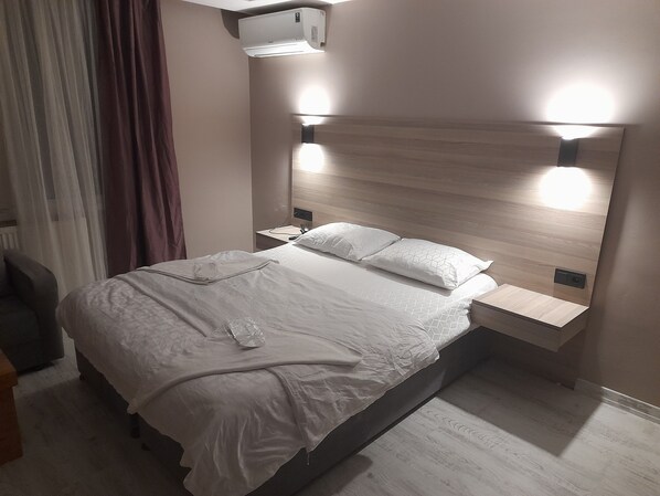 A modern hotel room with a large bed, bedside tables, a desk, and a wall-mounted air conditioner. - Moon Hotel Şirinevler (Istanbul)