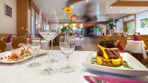 A dining table with a white tablecloth, two wine glasses, and a plate of food. - Luisenstuben (Badenweiler)