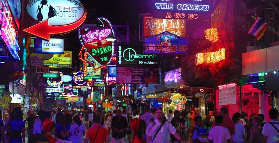 A busy street with neon signs and a crowd of people.