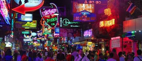 A busy street with neon signs and a crowd of people.
