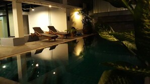 An indoor swimming pool with lounge chairs and potted plants. - Happy Bou Jomtien Guesthouse (Pattaya)
