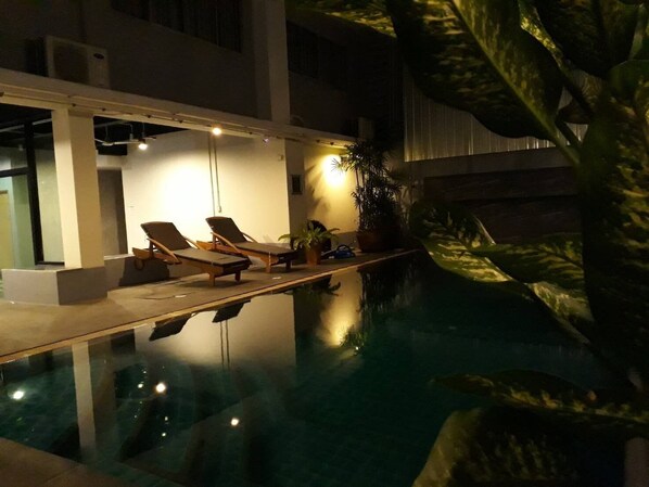 Una piscina interior con sillones de descanso y plantas en macetas.