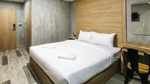 A modern hotel room with a large bed, wooden headboard, and a desk with a chair. - Happy Bou Jomtien Guesthouse (Pattaya)