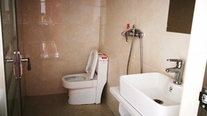 A bathroom with a toilet, a shower, and a sink. - DONG JIANG HU XIANG CUN DA WAN CAI Hotel (Chenzhou)