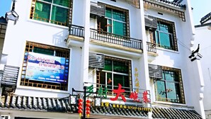 A multi-story building with a traditional architectural style, featuring a prominent red sign with Chinese characters. - DONG JIANG HU XIANG CUN DA WAN CAI Hotel (Chenzhou)
