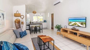 Een moderne woonkamer met een bank, salontafel, televisie en een keuken op de achtergrond.