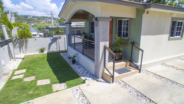 A house with a covered patio, a small lawn, and a stone pathway. - Your Home Away from Home (Montego Bay)