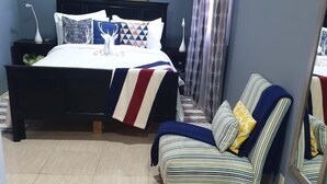 A bedroom with a bed, a chair, and artwork on the wall. - Your Home Away from Home (Montego Bay)