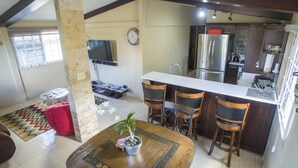 A modern kitchen with a central island, bar stools, a dining table with chairs, a red sofa, and a potted plant. - Your Home Away from Home (Montego Bay)