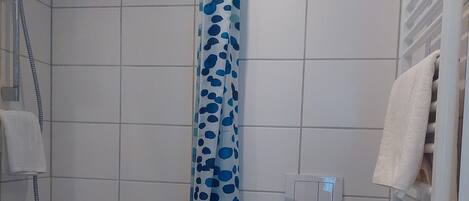 Un baño con ducha, inodoro y perchero para toallas.