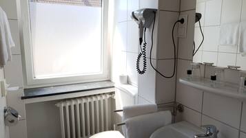 Un baño con inodoro, lavamanos y secador de pelo.