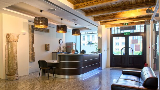 A reception area with a curved counter, a clock, and a Coca-Cola refrigerator. - Kamienica Pod Aniolami (Wroclaw)