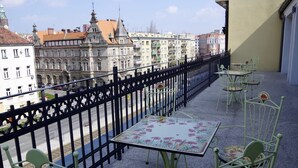 A balcony with a table and chairs, a black metal fence, and buildings in the background. - Kamienica Pod Aniolami (Wroclaw)