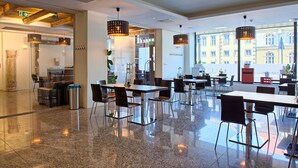 A modern hotel lobby with a polished granite floor, contemporary furniture, and large windows offering views of the city. - Kamienica Pod Aniolami (Wroclaw)
