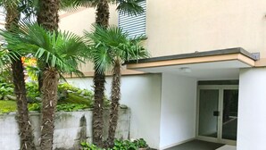 Edifício com parede de concreto, uma palmeira e porta de vidro.
