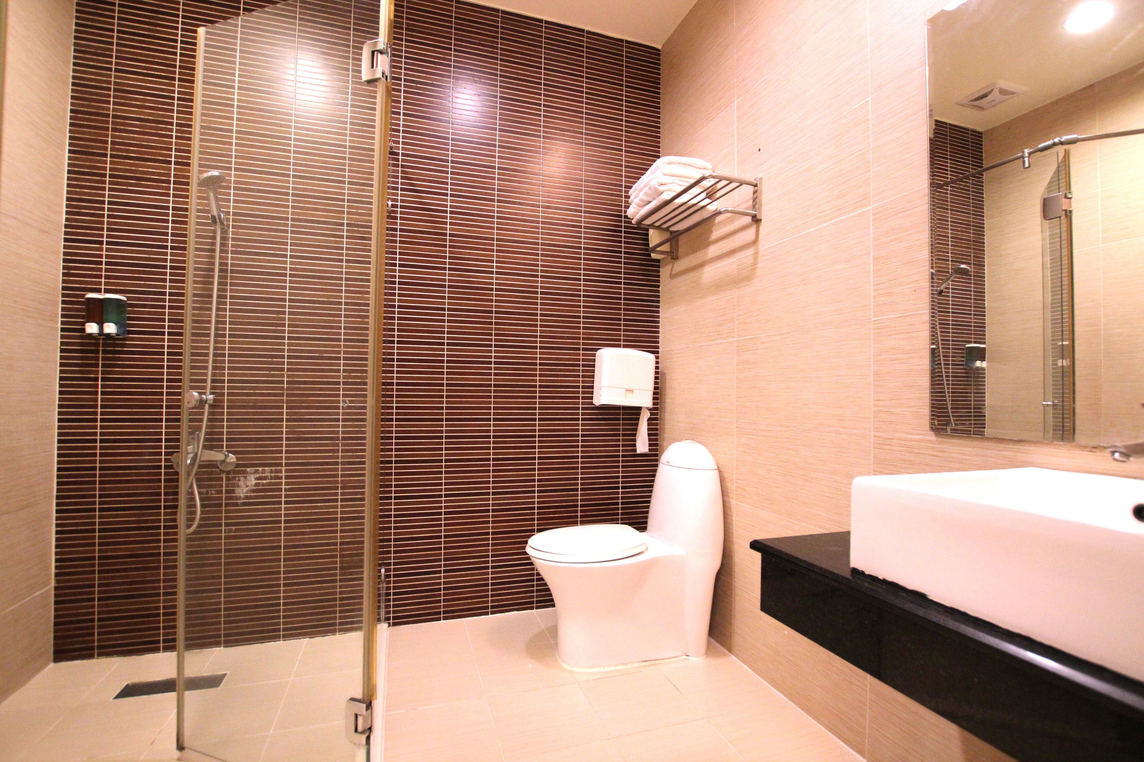A bathroom with a glass shower enclosure, a white toilet, and a large sink with a black countertop.